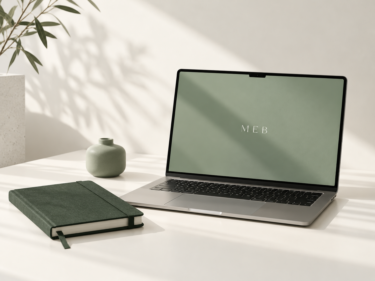 MEB workspace with a laptop and forest-green notebook
